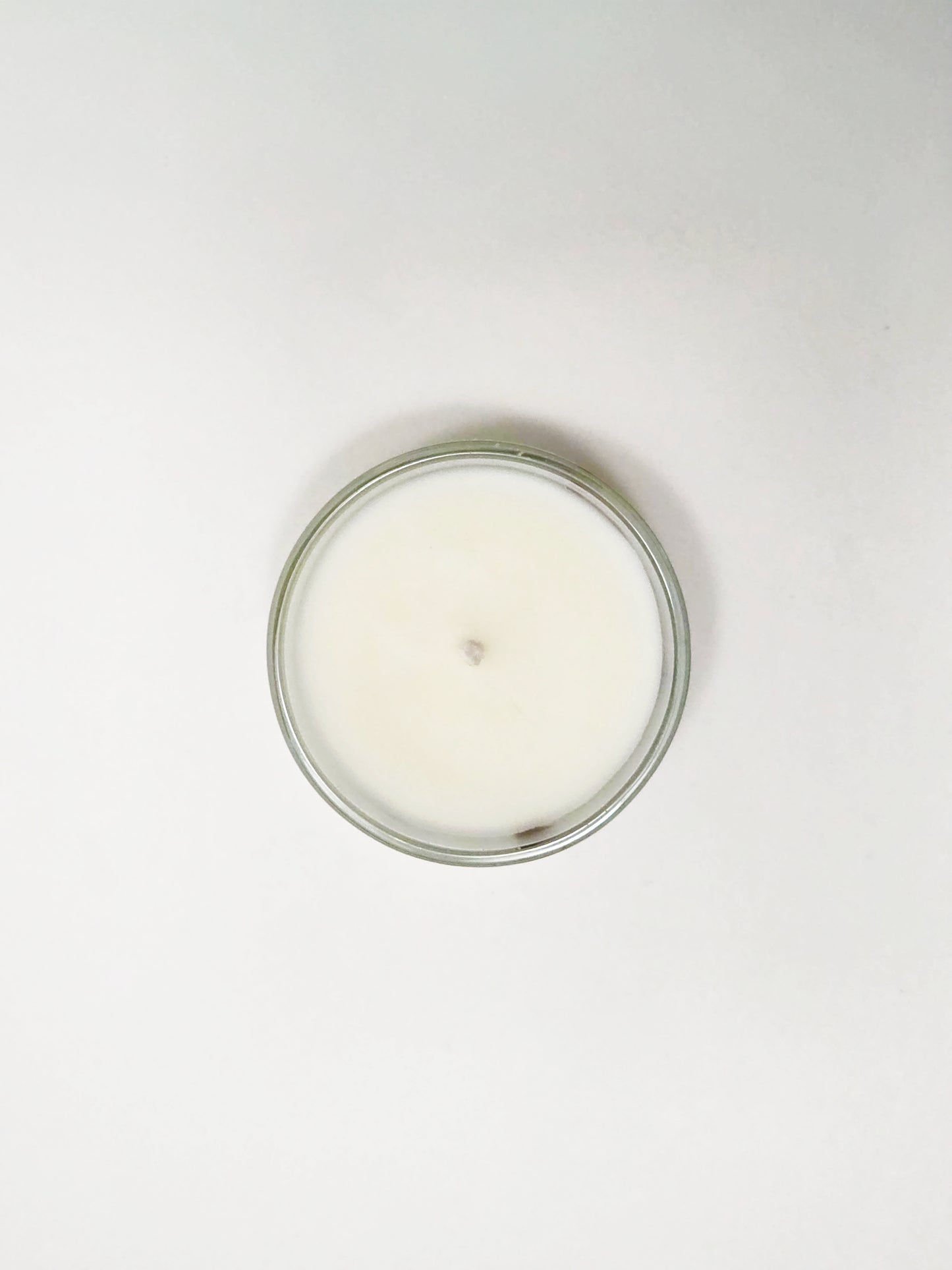 White candle in a glass jar on a white background