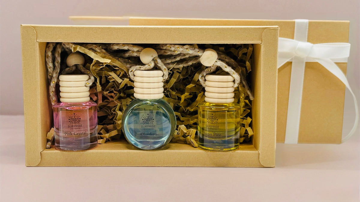 Bundle of Three small bottles of car fragrance in a decorative box with a beige background