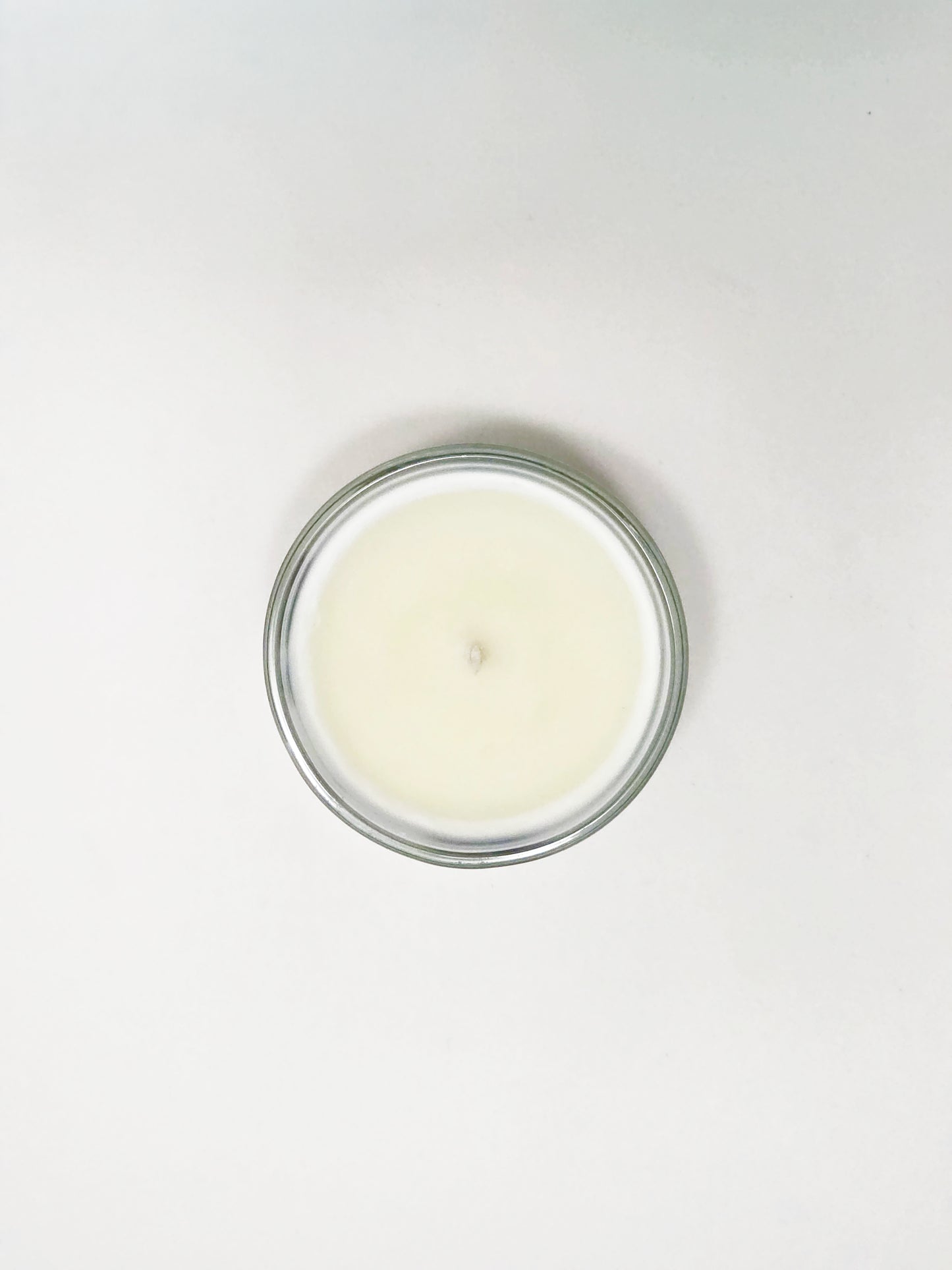 White candle in a glass jar on a white background