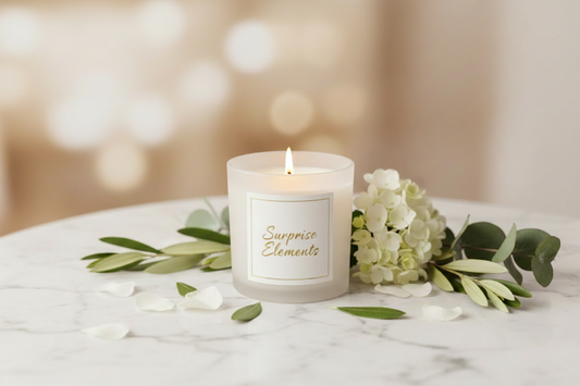 Surprise Elements luxury coconut wax candle burning on a marble table in an elegant spa-inspired setting with white florals and warm ambient lighting