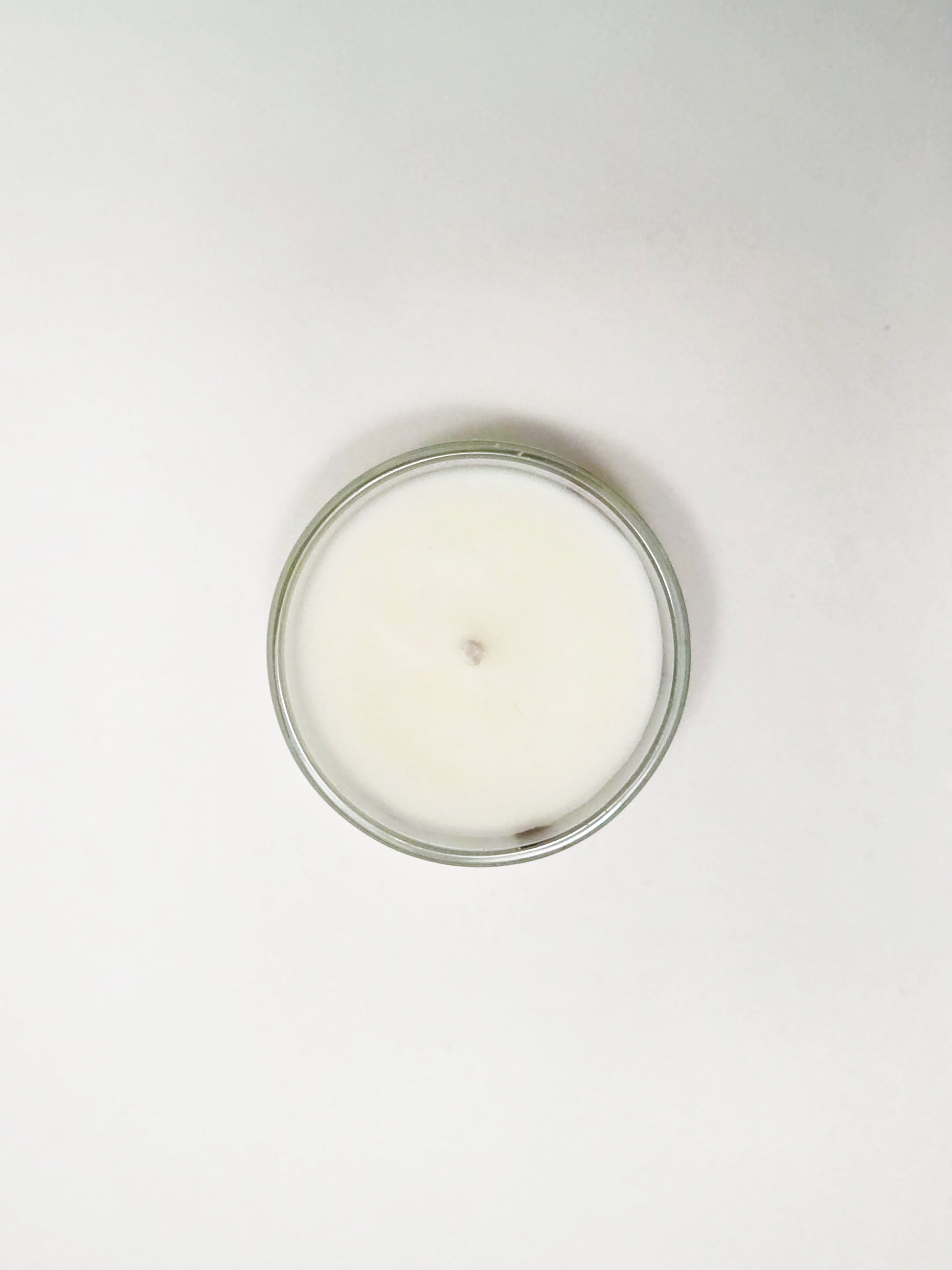 White candle in a glass jar on a white background