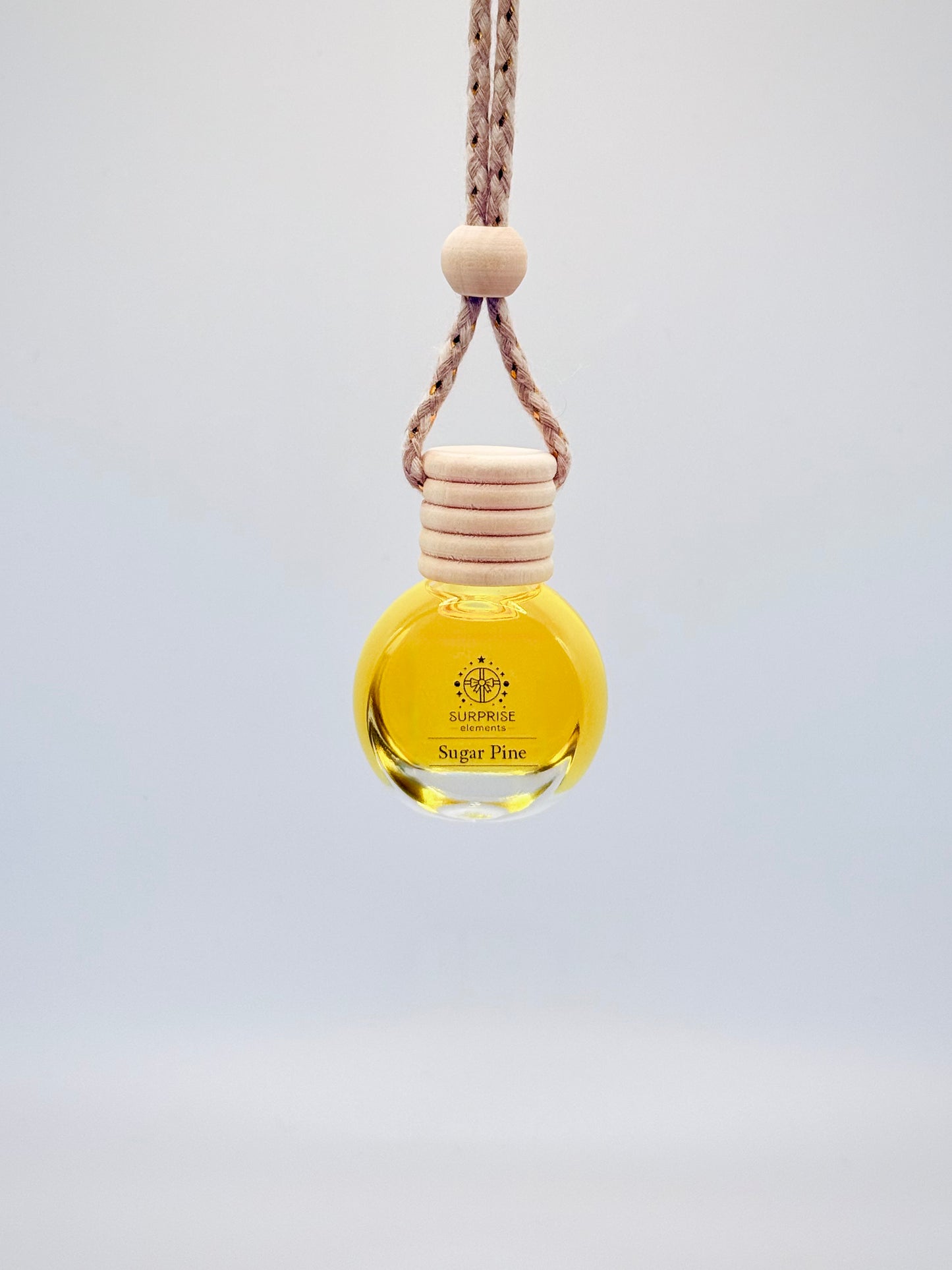 sugar pine car fragrance bottle with wooden cap and rope on a light gray background