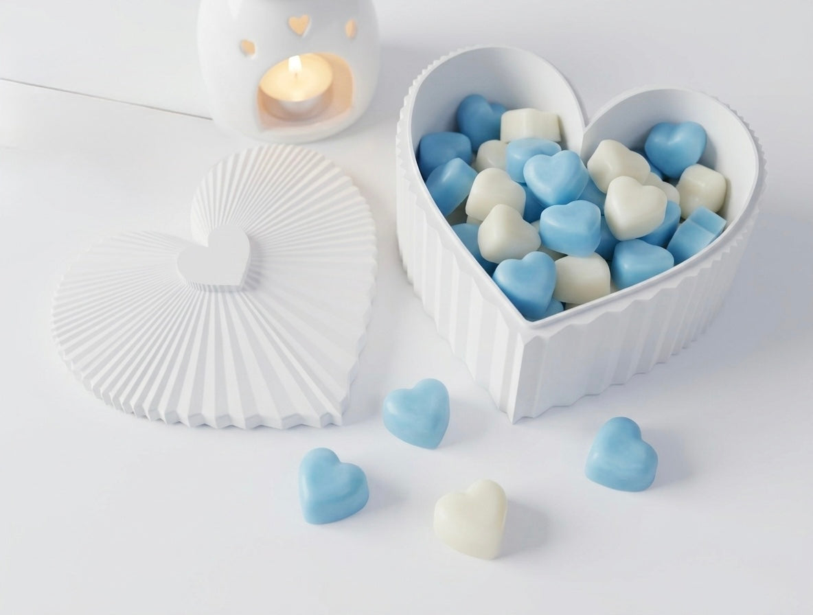 Heart-shaped container filled with blue and white heart-shaped wax melts on a light surface.