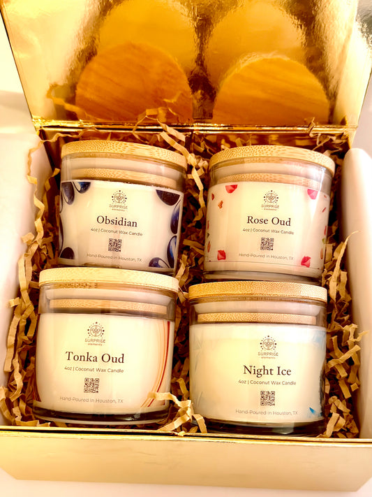 Four scented candles in a decorative box with visible labels. 